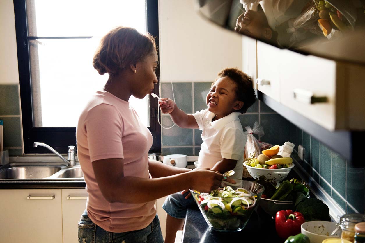 Child feeding mother in kitchen