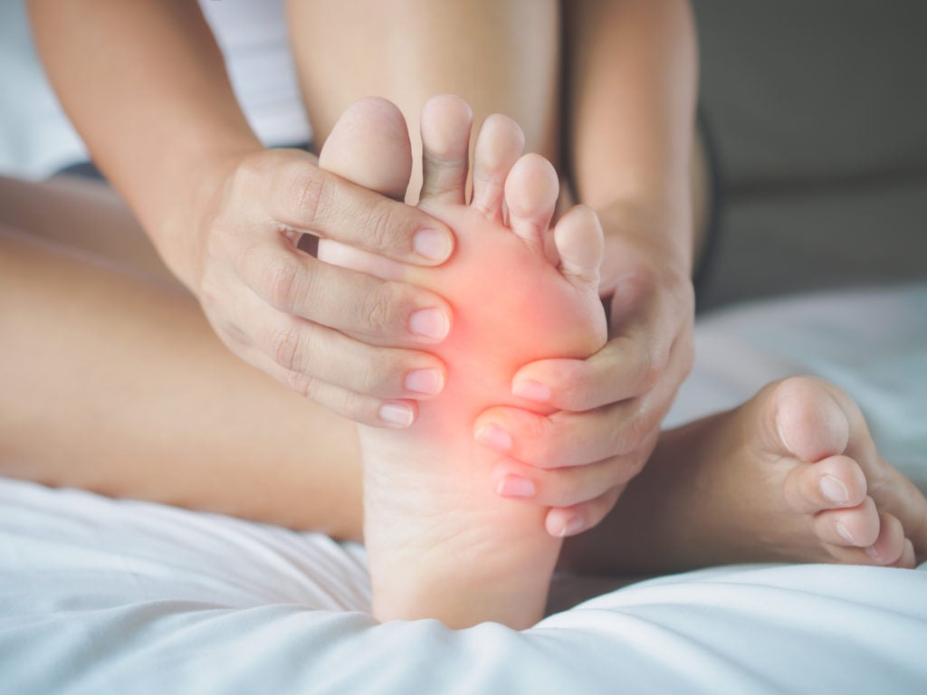 Closeup of young woman feeling pain in her foot