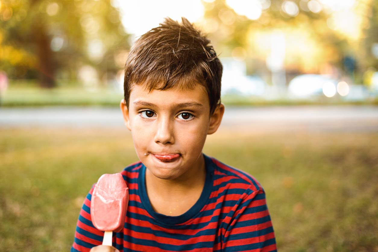 boy eating a popsicle outside