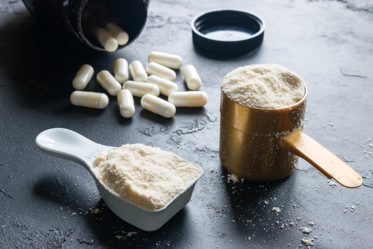 two measuring spoons of protein and creatine close-up on a black background