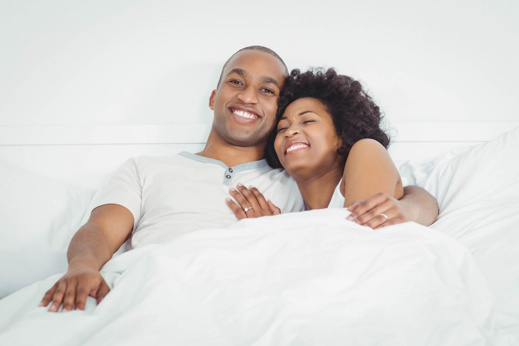 Happy couple on bed laughing