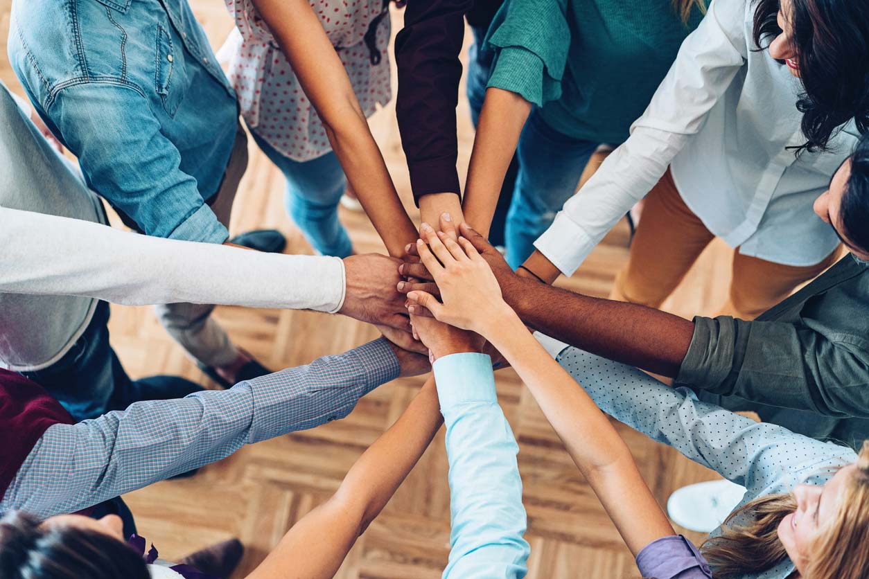 multi-racial hands in circle huddle