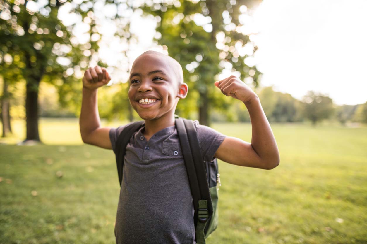 Young boy of color showing his muscles