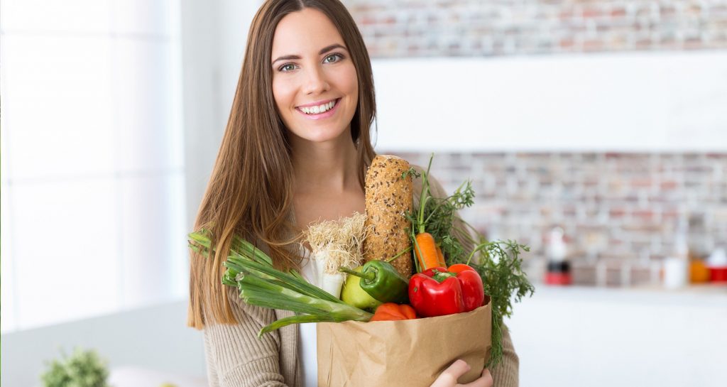 Woman holding a paper bag full of vegetables