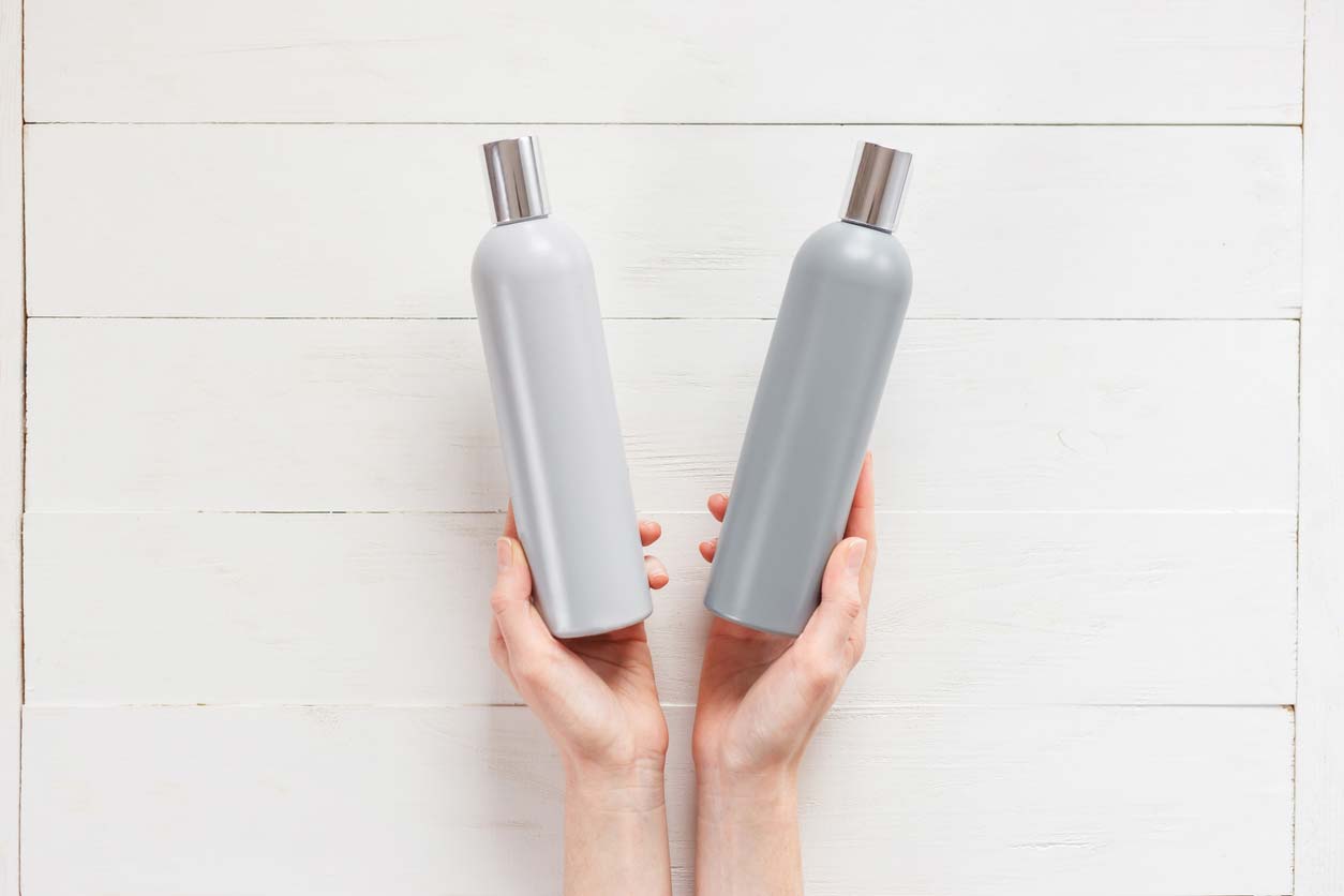 hands holding shampoo and conditioner bottles