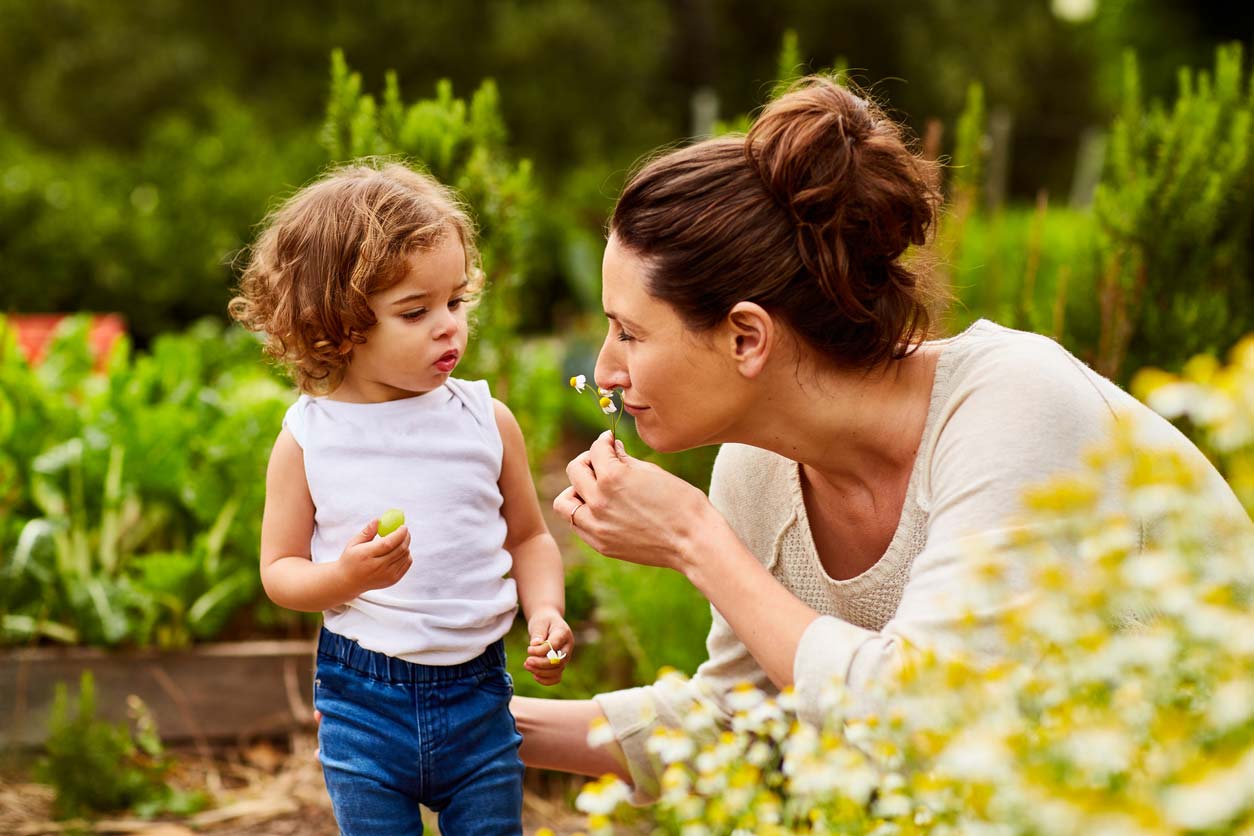 mom and daughter smelling daisies