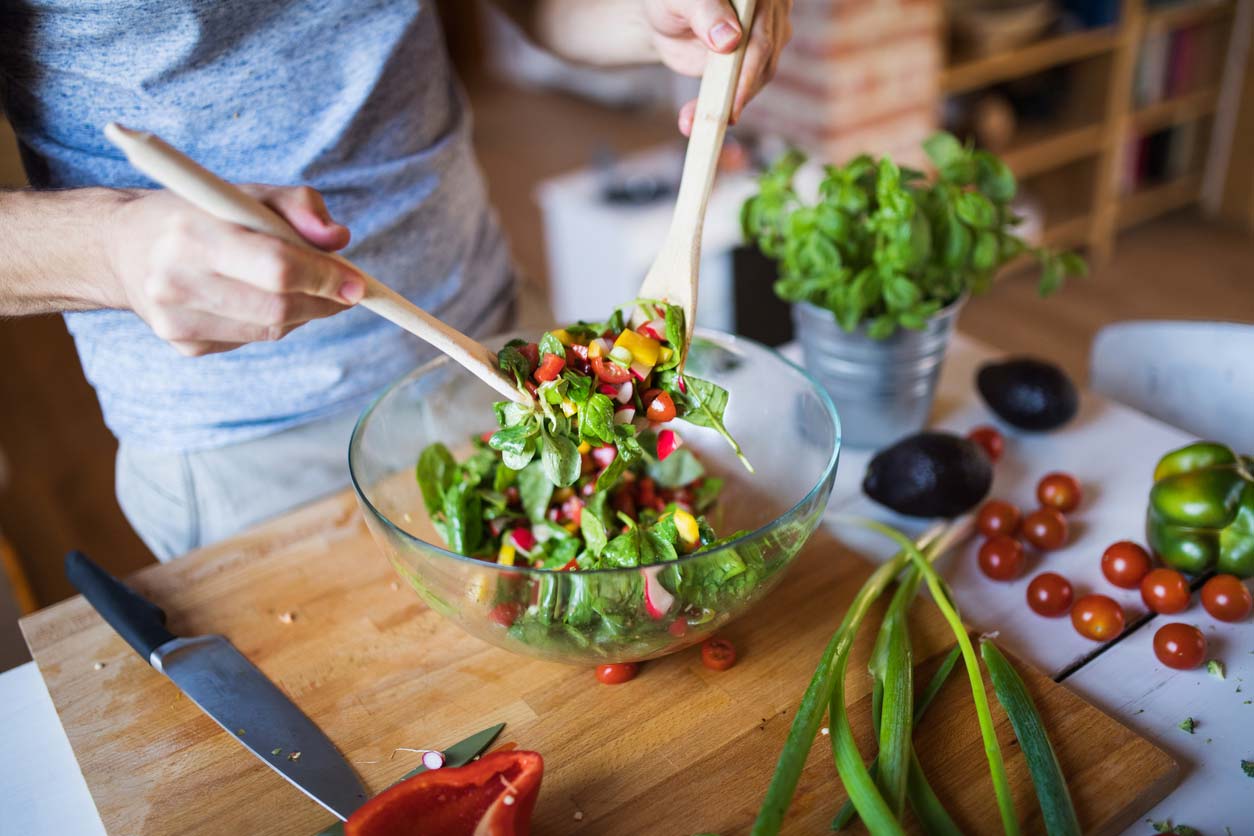 man tossing healthy salad in bowl