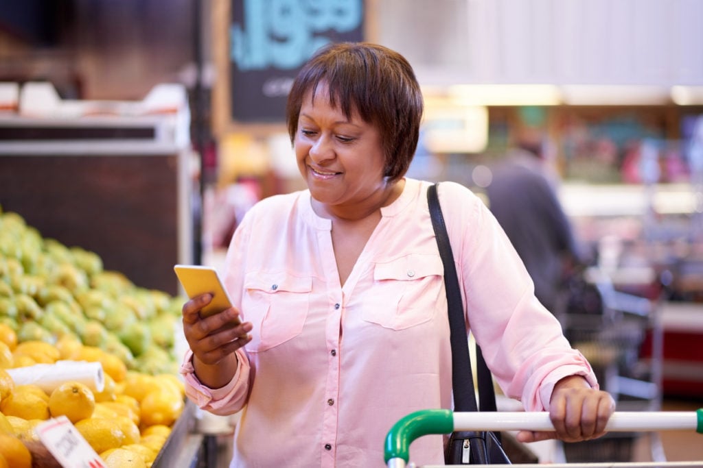 Shot of a mature woman using a mobile phone in a grocery store