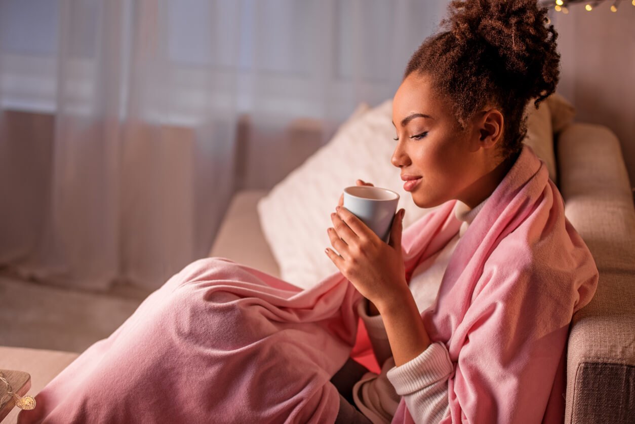 calm young woman enjoying hot beverage in living room