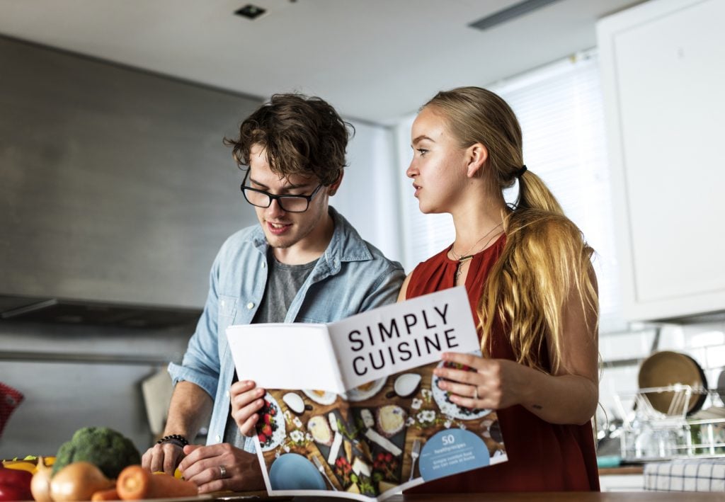 Teens in the kitchen cooking with a plant-based cookbook