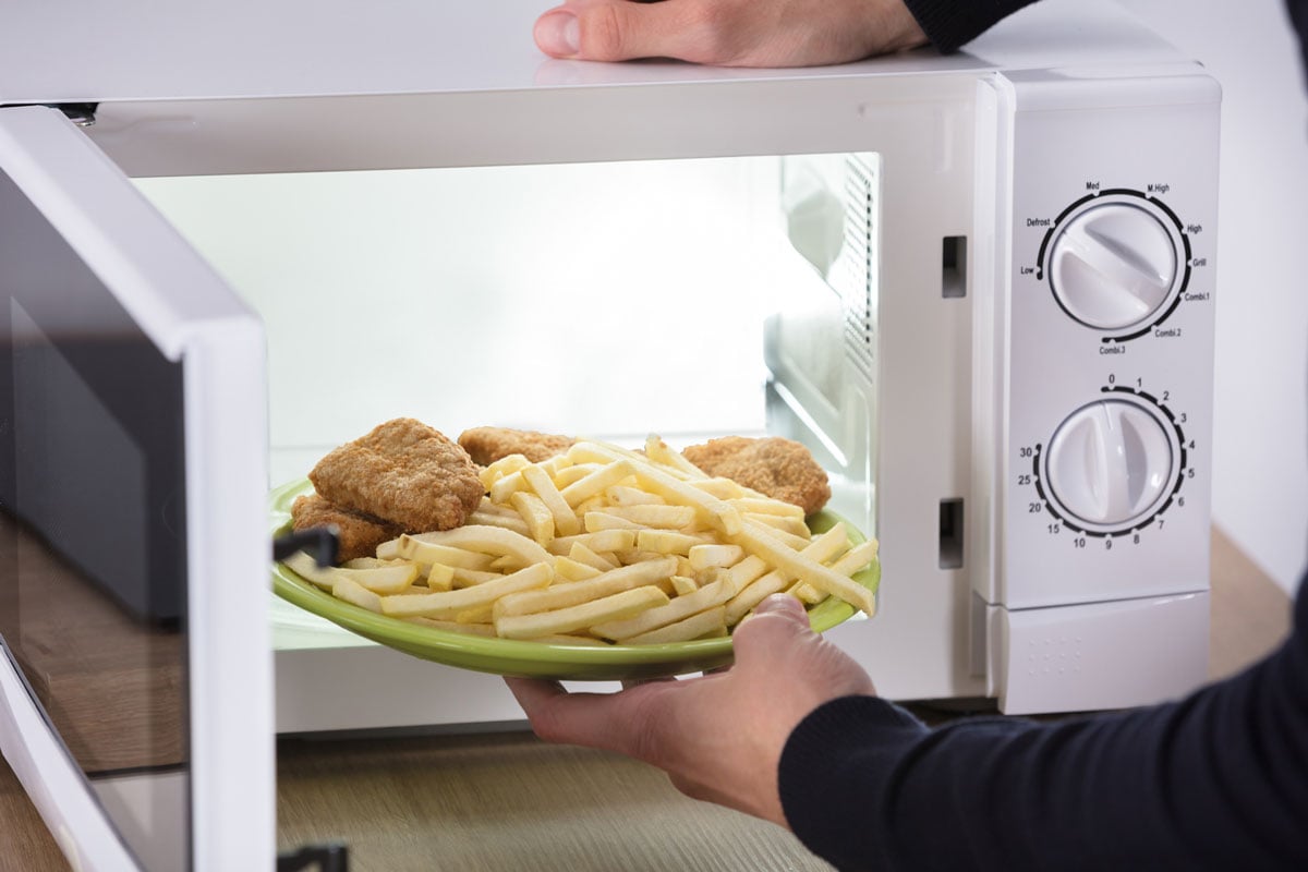 fries and battered chicken being placed in microwave