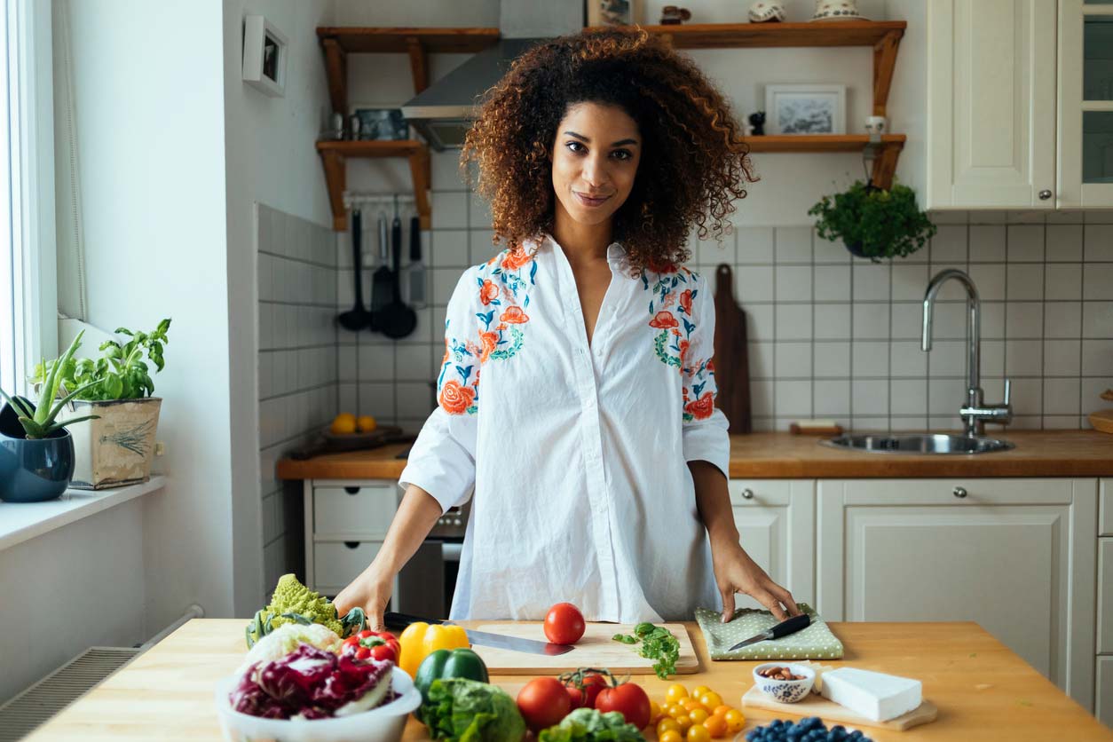 woman at cutting board preparing a raw foods recipe