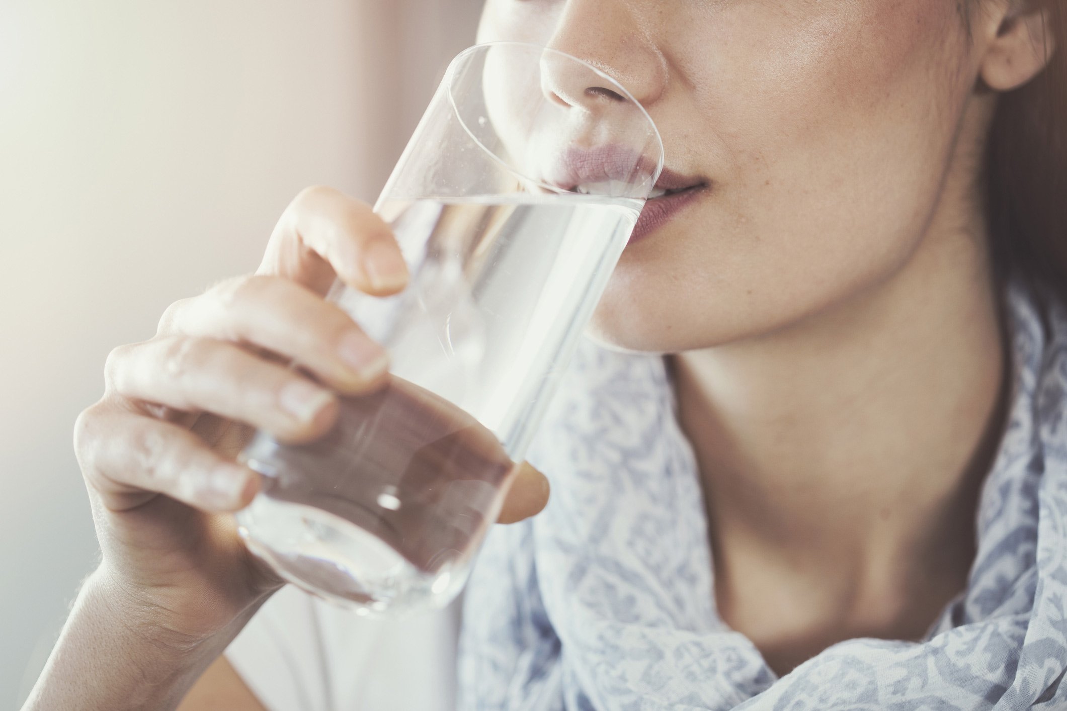 Woman drinking a glass of water with sediment