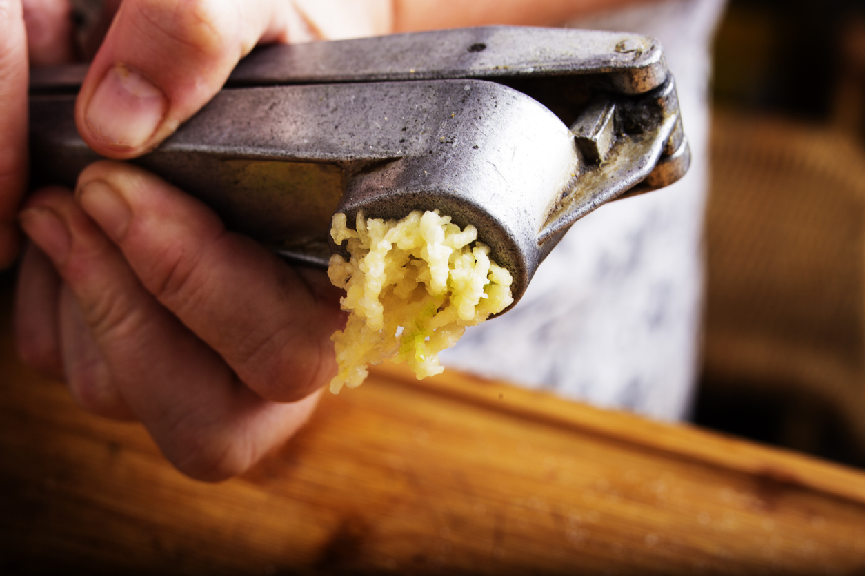 Crushing garlic with a garlic press in the kitchen.