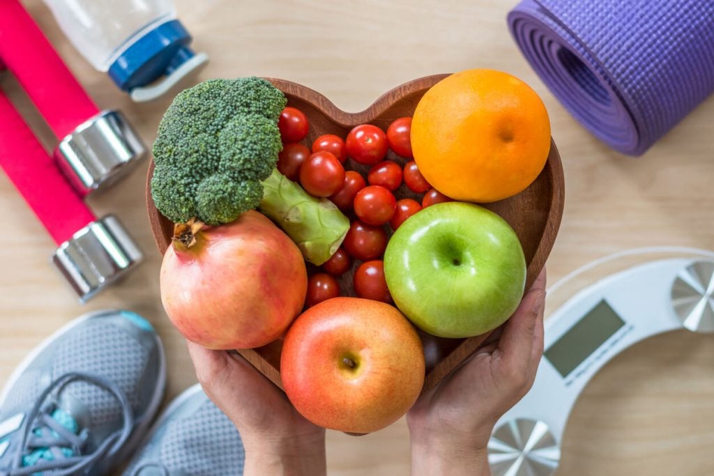 A heart shaped bowl of fruits and vegetables