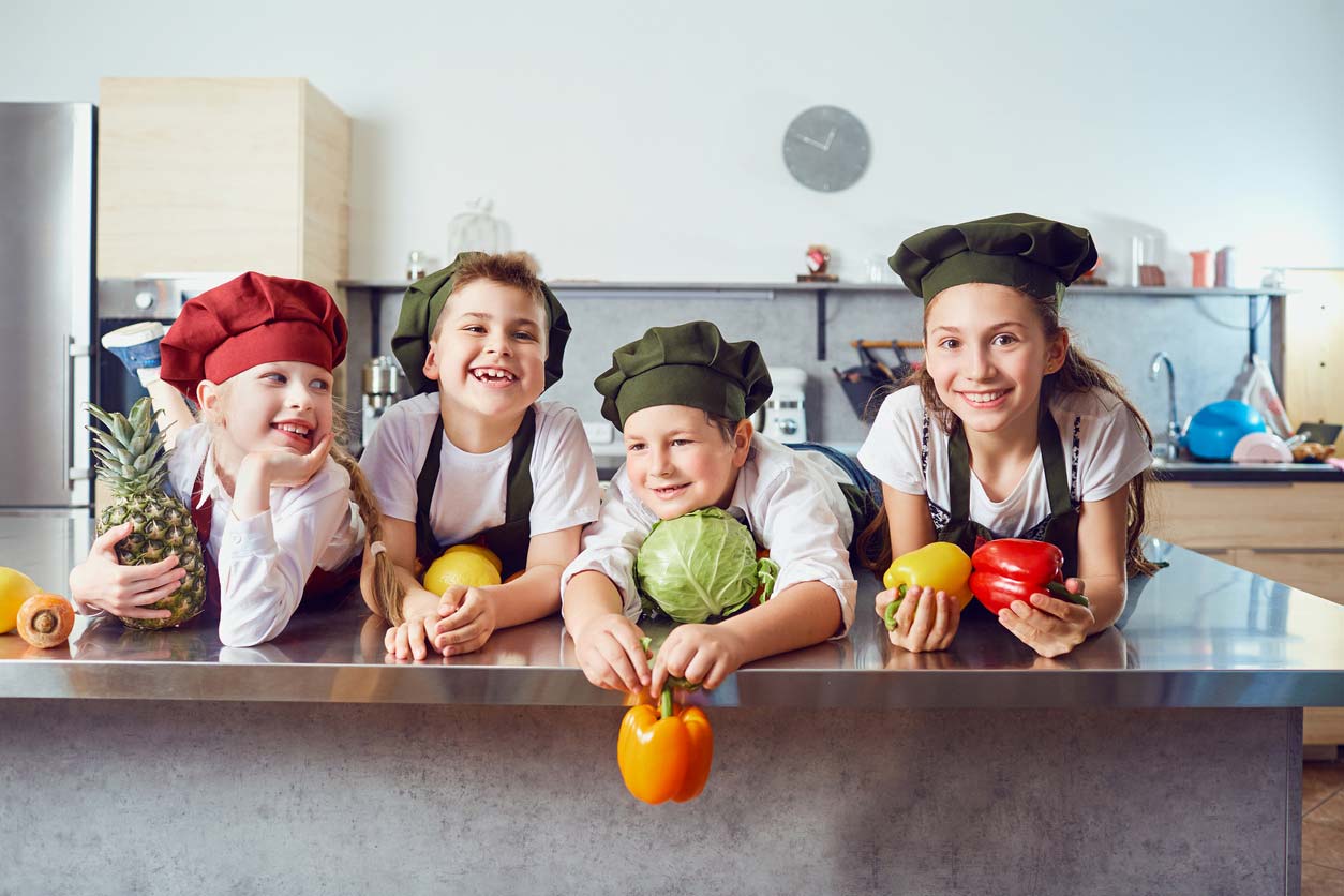 children in chef uniforms holding healthy foods