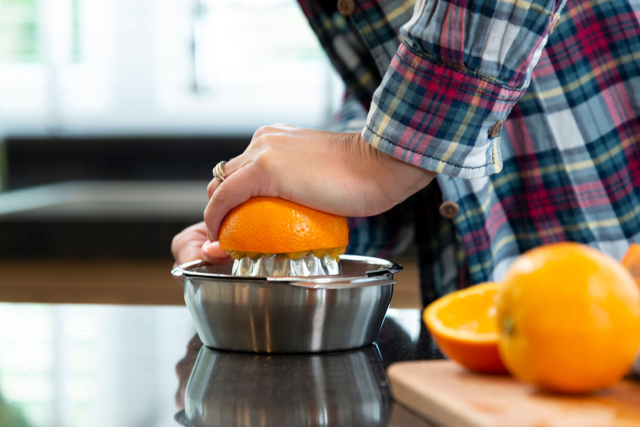 close up of hands of a woman squeezing oranges for juice