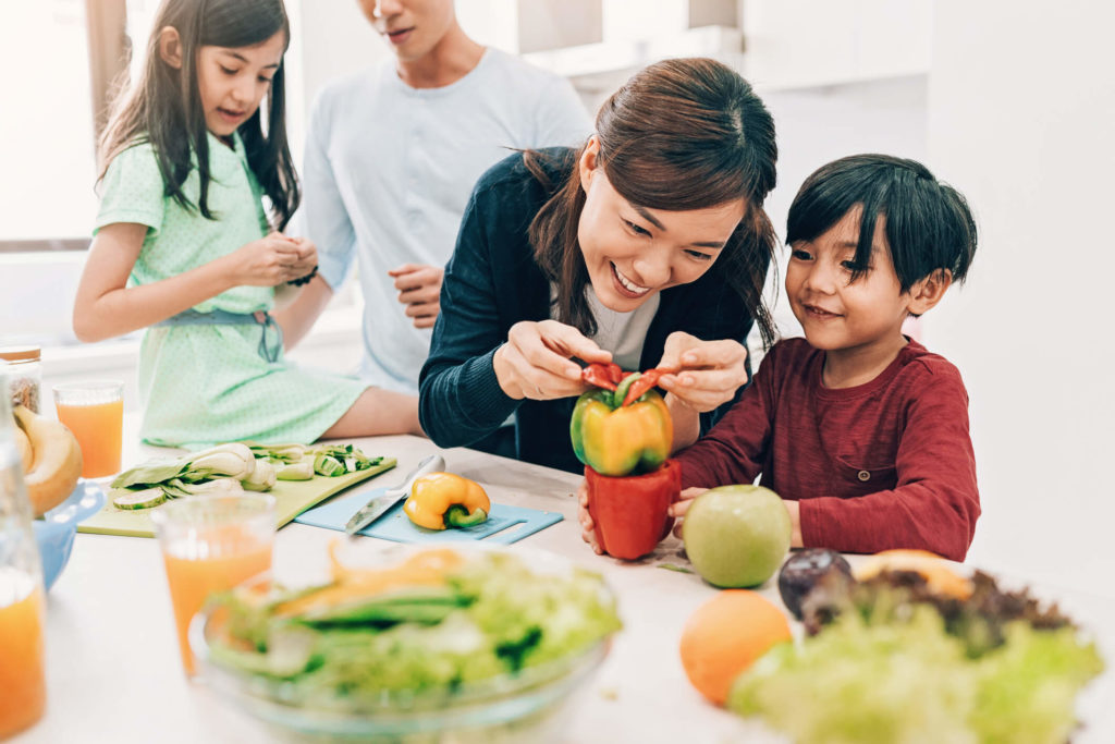 Asian parents with children showing them fruits and vegetables