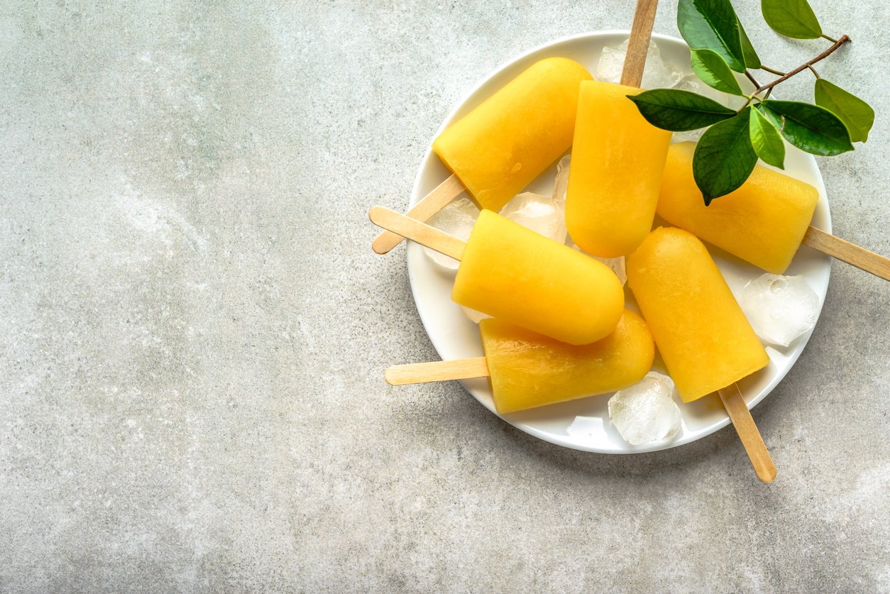 Homemade popsicles with orange juice, ice lollies on sticks, top view flat lay