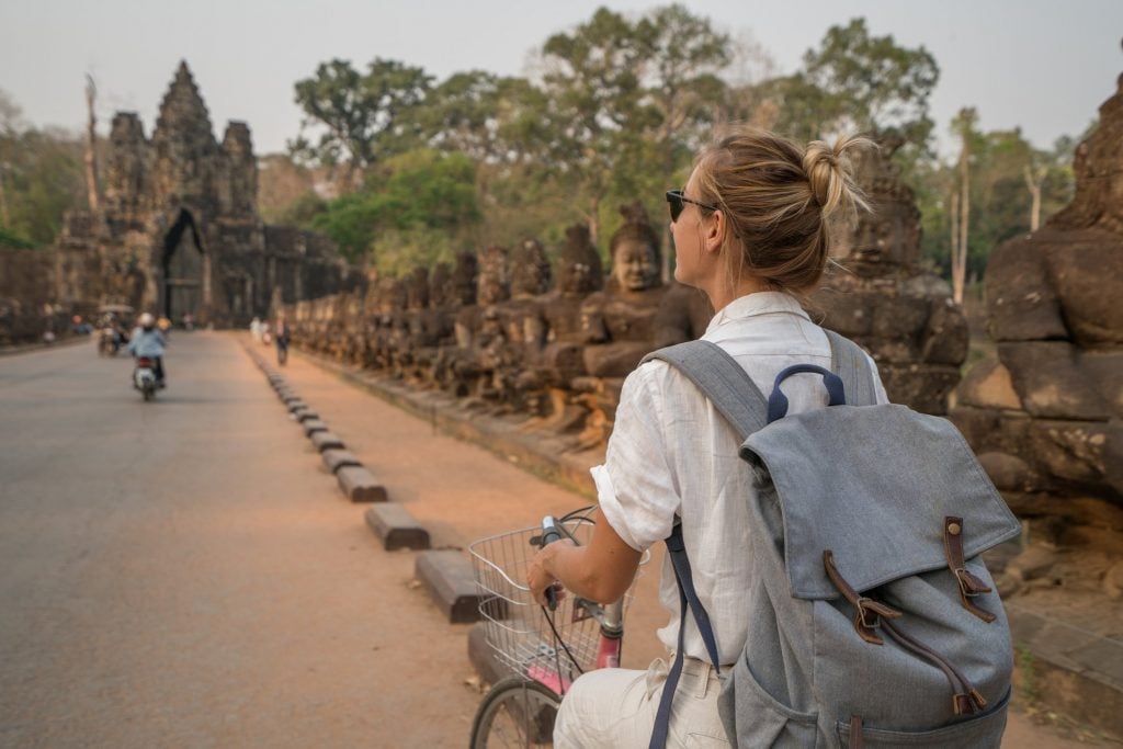 Young woman on bicycle in ancient temple complex in Cambodia