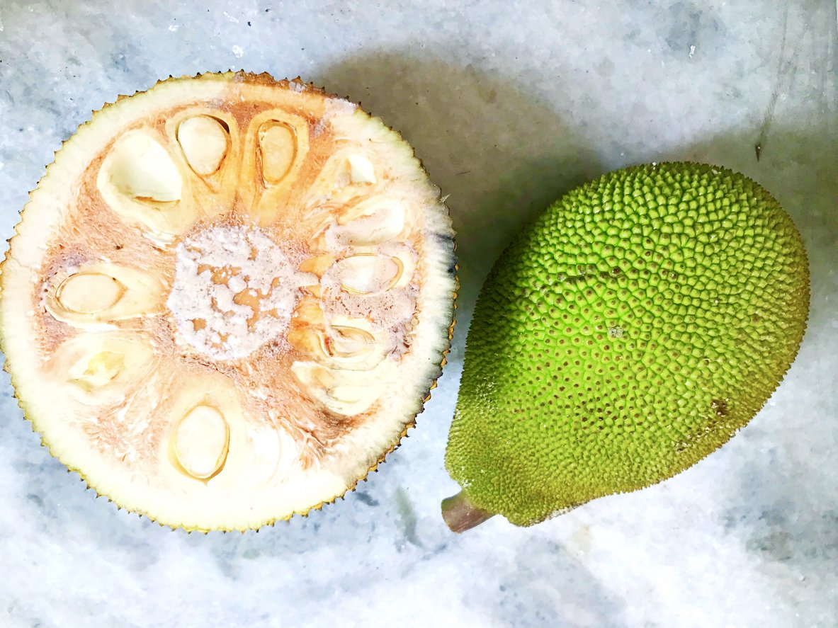 A green and raw jackfruit and a piece of this healthy fruit