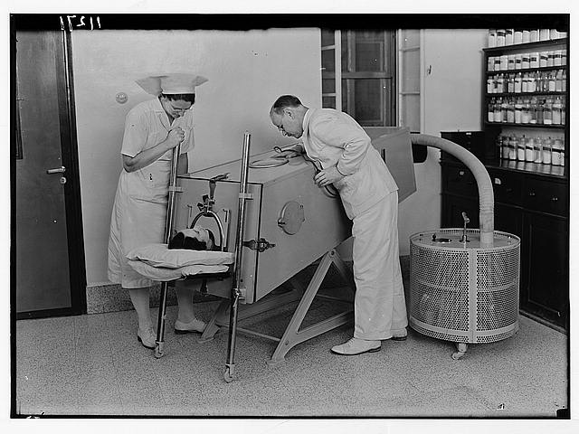 A doctor and nurse attending to a person in an iron lung